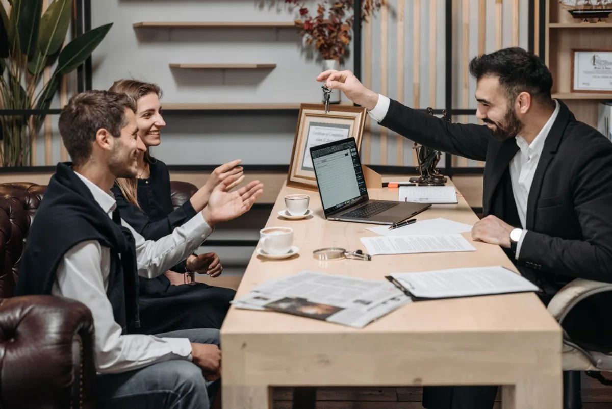 Agent passing keys across the table to buyers at closing