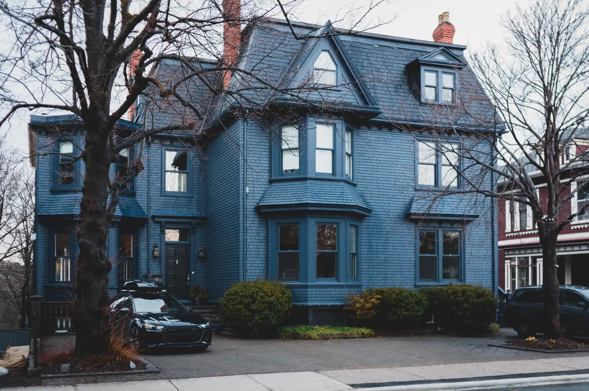 Blue three-story Victorian house with a mansard roof and bay windows