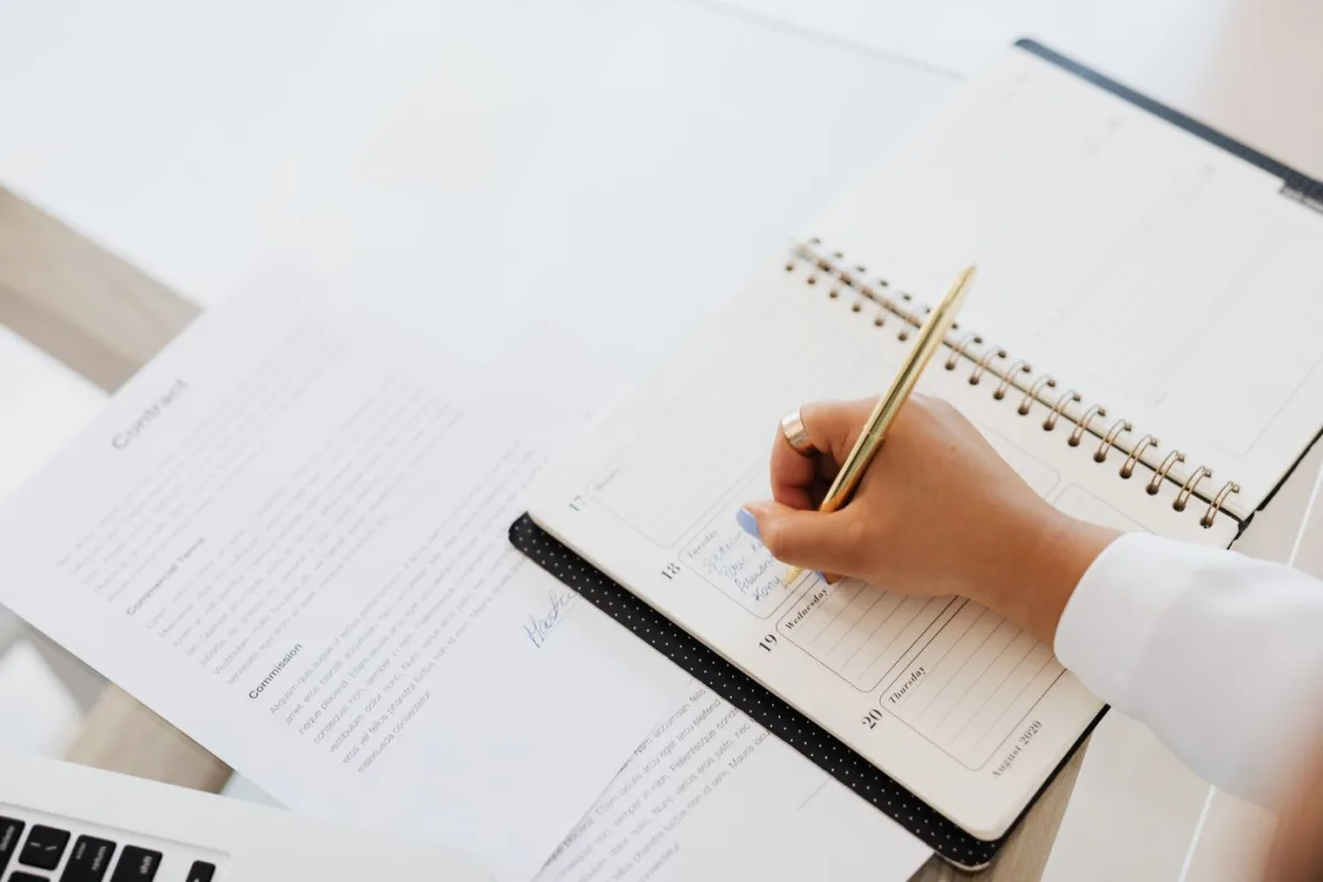 Contract dates being written into a planner beside the agreement