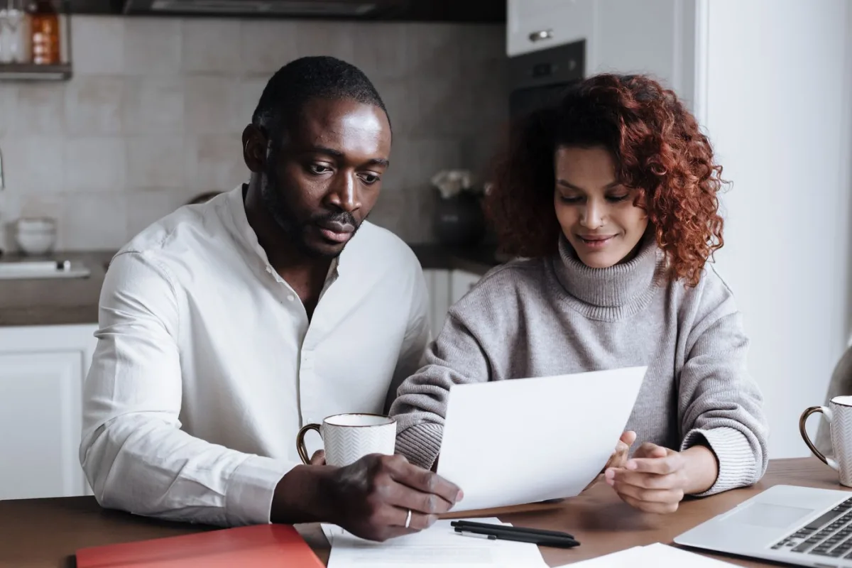First-time buyers reading the purchase contract at their kitchen table