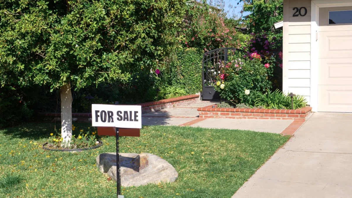 A home for sale sign in the front yard of a listed house