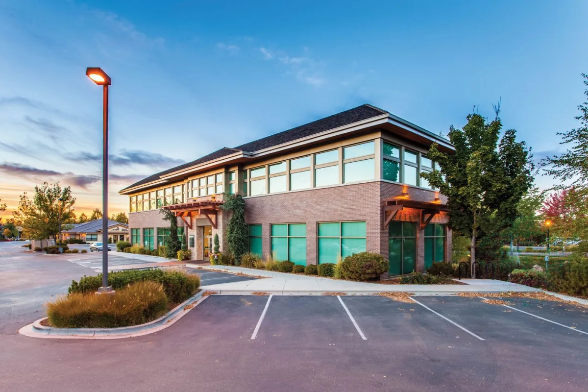 Two-storey brick office building with its parking lot at dusk