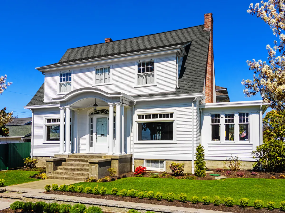 White two-story colonial home with a columned front porch and a landscaped yard
