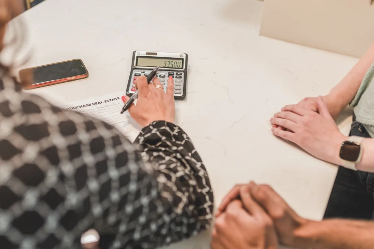 Agent working the numbers through on a calculator with clients at the table